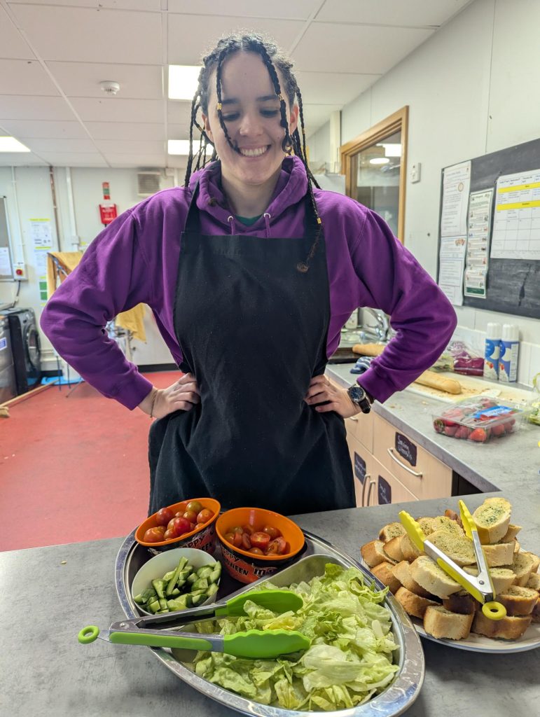 Playwoker smiling serving hot food to children with a disability and their families in Bristol