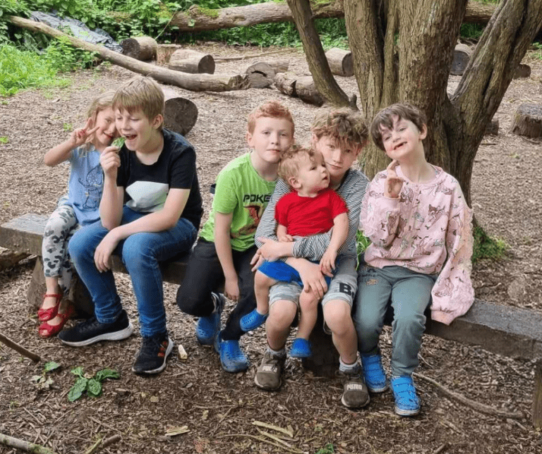 Group of children sitting on a log in the woods